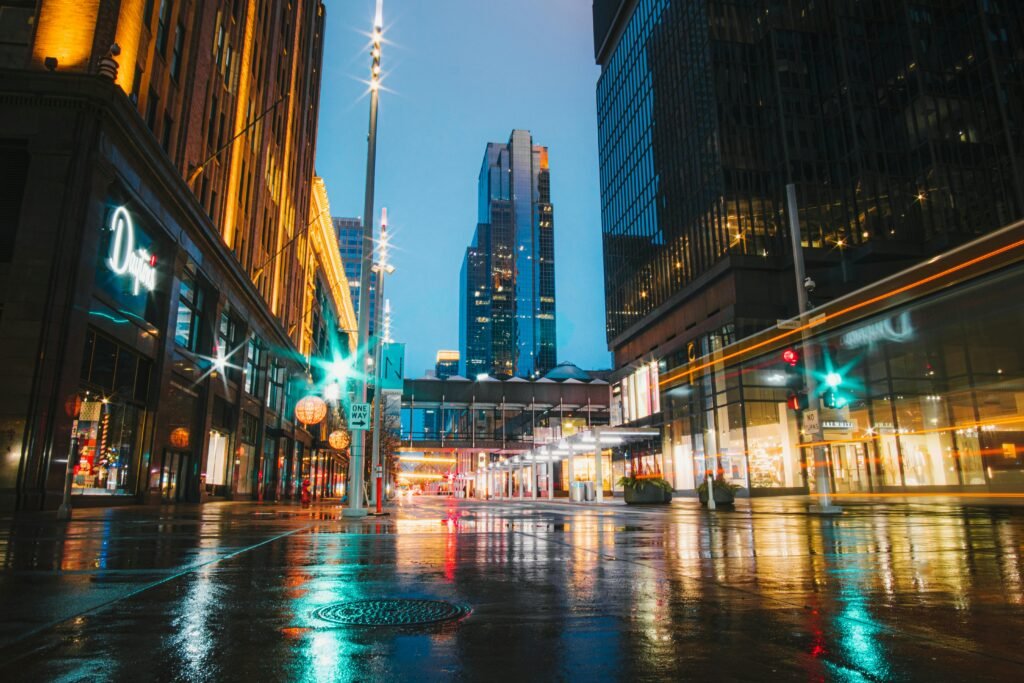 A vibrant view of the illuminated Minneapolis skyline at night with reflections on wet streets.